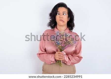 beautiful woman wearing pink shirt over white background making grimace and crazy face, screaming out of control, funny lunatic expressing freedom and wild.