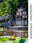 Beautiful woman wearing red dress and conical hat visiting Bich Dong pagoda in Ninh Binh Vietnam. Bich Dong Pagoda is a popular tourist destination of Asia.