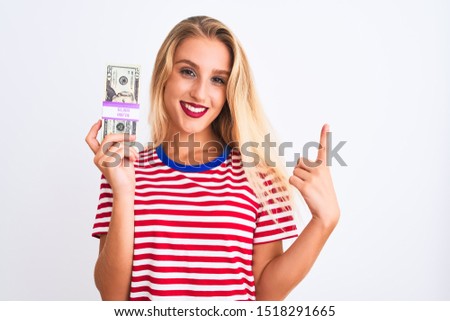 Beautiful woman wearing red striped t-shirt holding dollars over isolated white background surprised with an idea or question pointing finger with happy face, number one