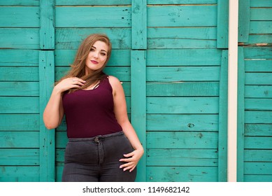 Beautiful woman wearing ripped jeans standing against cafe wall 