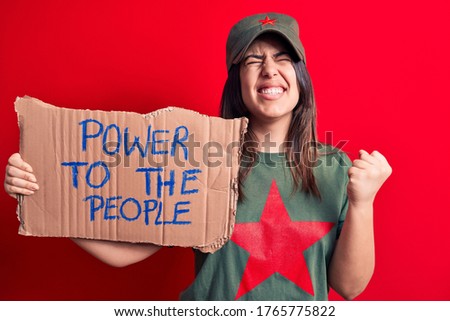Beautiful woman wearing t-shirt with red star communist symbol asking for social movement screaming proud, celebrating victory and success very excited with raised arm