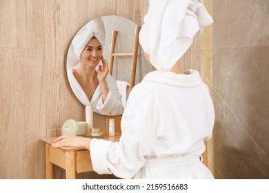 Beautiful woman wearing white bathrobe in front of mirror at home