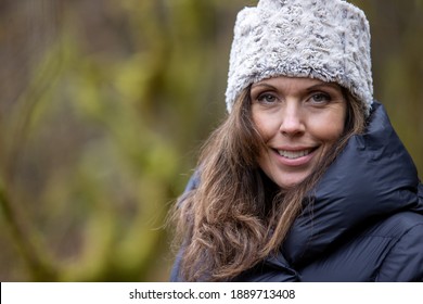 Beautiful Woman Wears Winter Hat And Puffy Coat Outside In The Forest