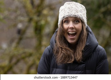 Beautiful Woman Wears Winter Hat And Puffy Coat Outside In The Forest