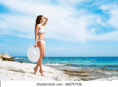 Beautiful woman in white bikini. Young and sporty girl posing on a beach at summer.