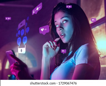 Beautiful Woman With White Eyes Using Interface Modern Technology And Digital Layer Effect For Social Media Displaying. Bright Neon Icons Around Her. Concept Of Digital, Tech, Communication, Future.