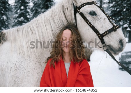 Beautiful woman with white horse in winter fir forest 