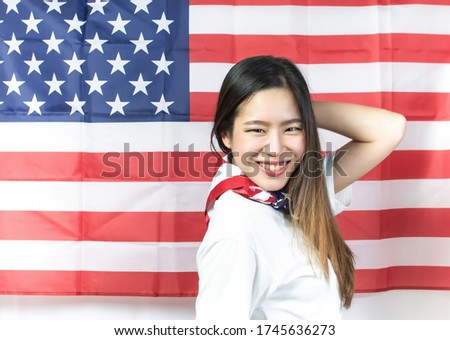A beautiful woman in white shirt smiling and posing with background of american flag for celebrating national independence day on 4th of July