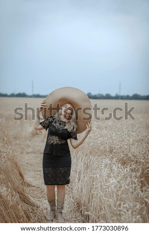 a beautiful woman in a wide-brimmed straw hat is resting in a wheat field