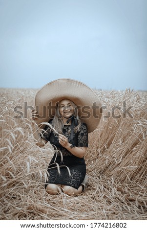 a beautiful woman in a wide-brimmed straw hat is resting in a wheat field