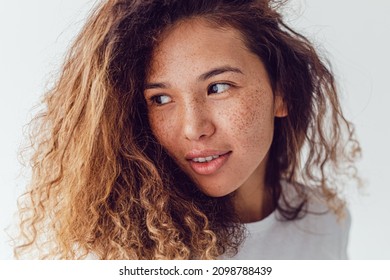 Beautiful woman without makeup with natural curly hair and clean skin with freckles.