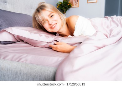 Eine schöne Frau wachte in einem rosa Bett auf. Erholen Sie sich im Hotel. rosafarbenes Seidenbett.