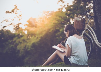 beautiful woman writing into her diary, in the park