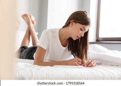 Beautiful Woman Writing Notes While Lying In Bed