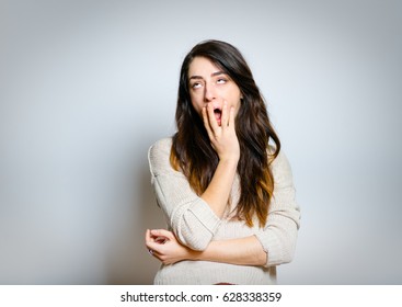 Beautiful Woman Yawns, Bored, Isolated On Gray Background