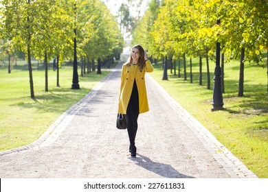 Beautiful Woman In Yellow Coat Walking Autumn Street