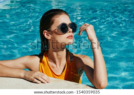 Beautiful woman yellow swimsuit sunglasses in the pool luxury health vacation