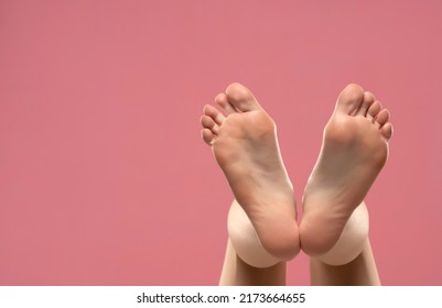 Beautiful Woman's Bare Feet Against A Pink Background.