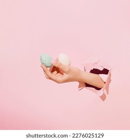 Beautiful woman's hand holding Easter eggs. Pastel pink torn paper. Seasonal background. Minimal holiday concept, copy space. - Powered by Shutterstock