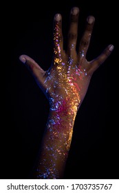 beautiful woman's hands with unusual cosmic prints, fluorescent paint on hands glowing on neon lights. isolated black background