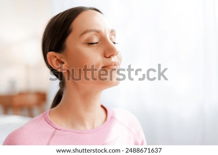 Beautiful women with closed eyes breathing while relaxing after exercising workout, resting from exercises at home