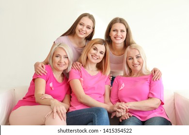 Beautiful women of different ages with pink ribbons sitting on sofa in room. Breast cancer concept - Shutterstock ID 1415354522