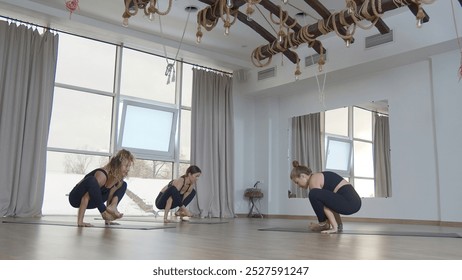 Beautiful women do yoga in studio. Media. Professional yoga classes in sunny studio. Young women perform yoga exercises with instructor - Powered by Shutterstock