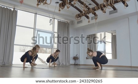 Beautiful women do yoga in studio. Media. Professional yoga classes in sunny studio. Young women perform yoga exercises with instructor