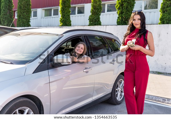 Beautiful women with\
dollars and keys near\
car