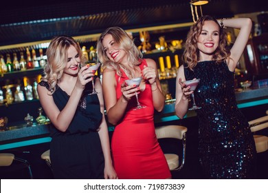Beautiful women drink cocktails and dance in the bar.