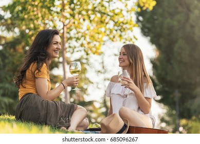 Beautiful Women Drinking Wine In The Park. Friends And Summer Concept.