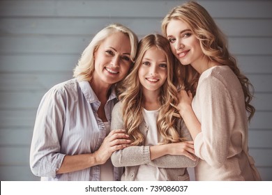 Beautiful women generation: granny, mom and daughter are hugging, looking at camera and smiling