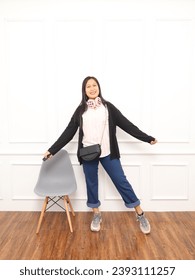 Beautiful women are happy because they are free from all burdens.  Woman wearing backwards sweater, jeans, shoes, standing with arms outstretched on white background studio.