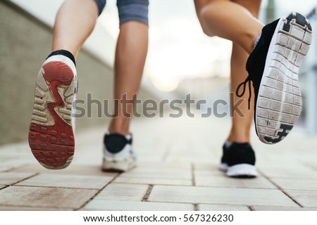Beautiful women jogging on pavement in city and feets are in focus