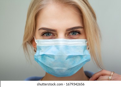 Beautiful Women In A Medical Mask. Close-up of a young woman with a surgical mask on her face against SARS-cov-2. - Shutterstock ID 1679342656