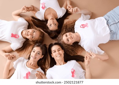 Beautiful women with pink ribbons holding hands on beige background, top view. Breast cancer awareness concept - Powered by Shutterstock