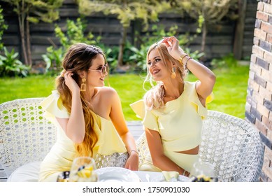 beautiful women sit in nature communicate and share secrets, they are dressed in a yellow dress and beautiful jewelry, they enjoy life smile and laugh, the concept of the joy of life