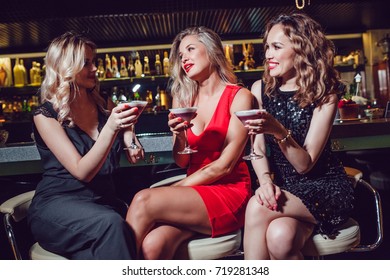 Beautiful Women Are Sitting On The Bar And Drinking Cocktails.