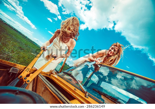 Beautiful women with tools are repairing a car on\
the rural road