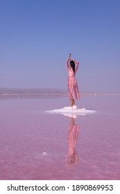 Beautiful women tourist in pink long dress walking in water on pink salt Lake Tuz. Ankara. Tuz Golu Lake is the second largest lake in Turkey and one of the largest hypersaline lakes in the world
