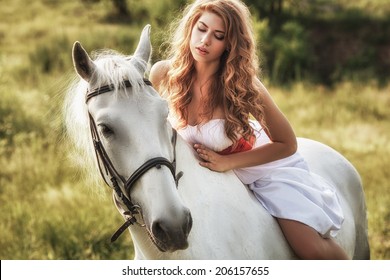 Beautiful women wearing white dress riding on white horse 