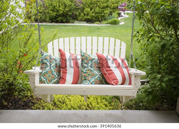 Beautiful wooden front porch swing with\
comfortable pillows