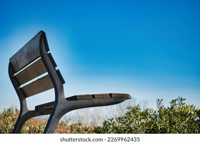 Beautiful wooden and metal bench on a hill in a park with blue sky in the background.