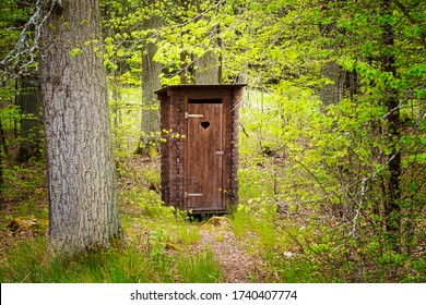 beautiful wooden professionally repaired outhouse in a green forest serves as a toilet in nature