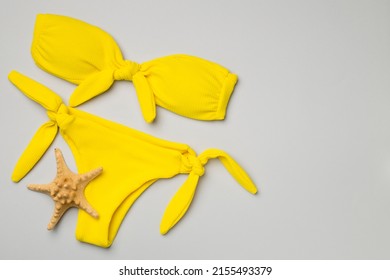 Beautiful yellow bikini on color background, top view.