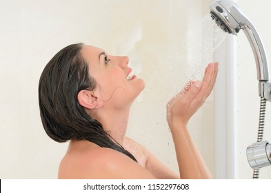 Beautiful youmg woman taking a shower enjoying water splashing on her 