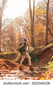 Beautiful young active woman crossing the creek while hiking on a sunny autumn day in forest, spending her vacation outdoors in nature