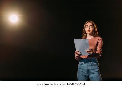 beautiful young actress reading scenario on black