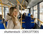 Beautiful young adult caucasian woman stands in the bus and looks into the distance