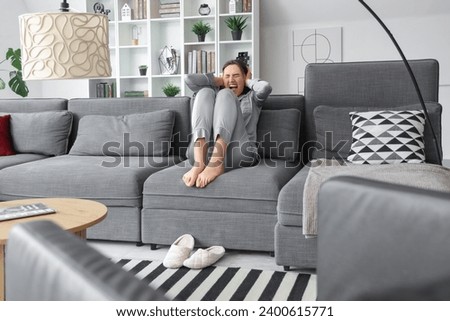 Beautiful young afraid woman sitting on sofa and screaming in living room